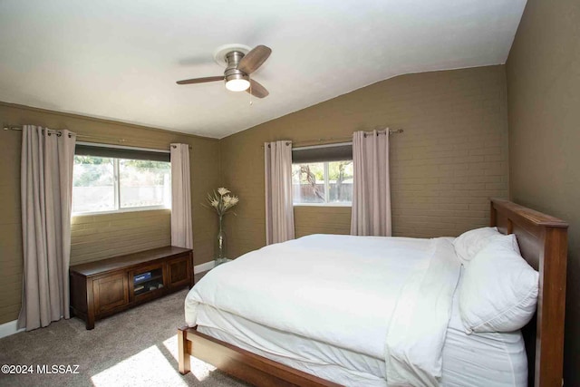 carpeted bedroom with ceiling fan, brick wall, and vaulted ceiling