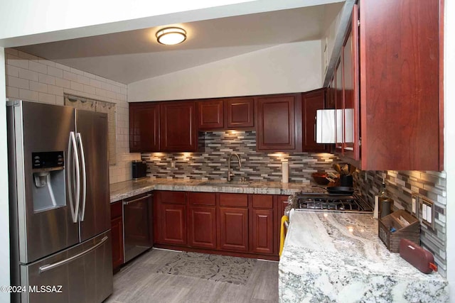 kitchen with decorative backsplash, sink, light stone countertops, and appliances with stainless steel finishes