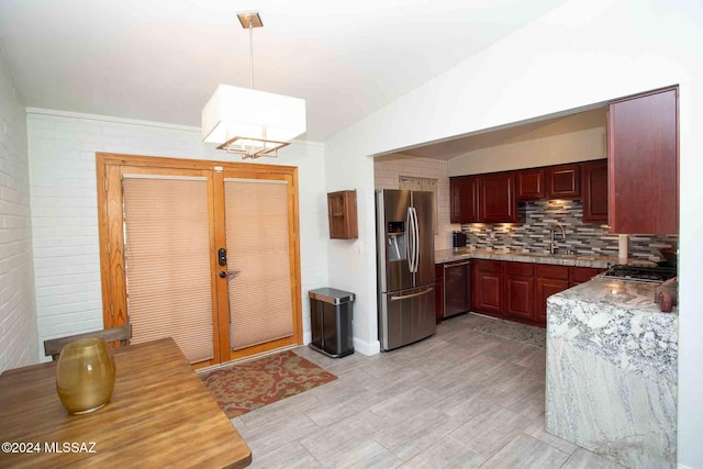 kitchen featuring decorative backsplash, brick wall, stainless steel appliances, sink, and hanging light fixtures