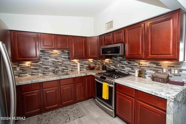 kitchen featuring light stone countertops, sink, appliances with stainless steel finishes, and tasteful backsplash