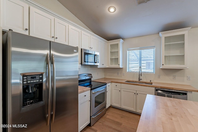 kitchen with wood counters, lofted ceiling, sink, appliances with stainless steel finishes, and white cabinets