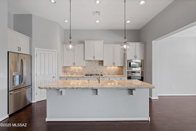 60241 E Arroyo Grande Dr, Oracle, AZ 85623 - kitchen featuring appliances with stainless steel finishes, a breakfast bar, decorative backsplash, white cabinetry, and recessed lighting