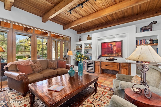 living room featuring beam ceiling, beverage cooler, built in shelves, and rail lighting