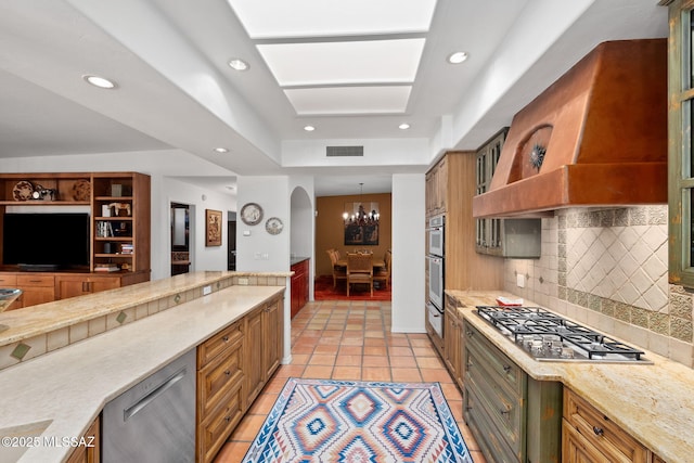 kitchen featuring appliances with stainless steel finishes, light tile patterned floors, a notable chandelier, custom range hood, and tasteful backsplash