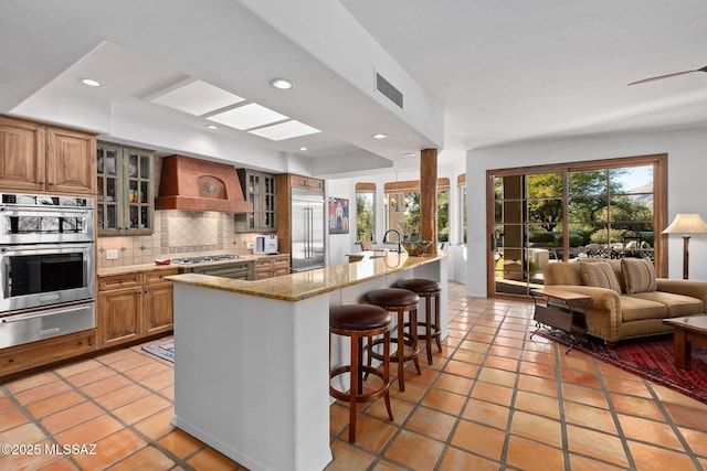 kitchen with plenty of natural light, a breakfast bar, custom exhaust hood, and stainless steel appliances