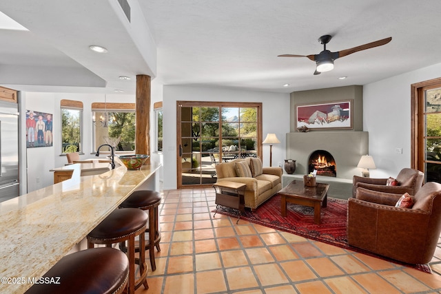 living room featuring sink, tile patterned floors, and ceiling fan with notable chandelier