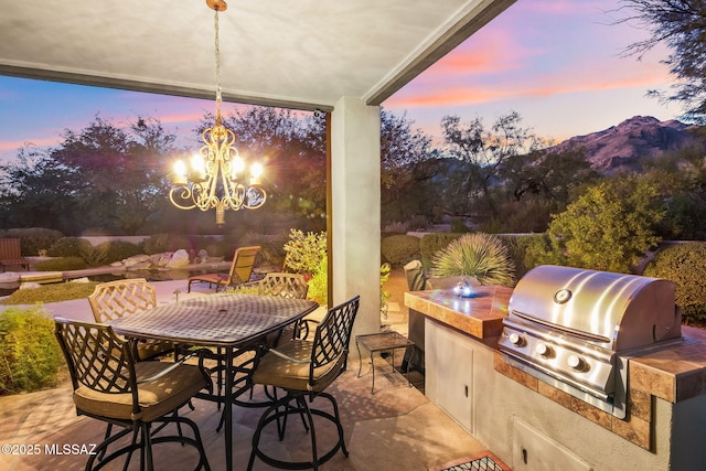 patio terrace at dusk featuring area for grilling, a mountain view, and grilling area