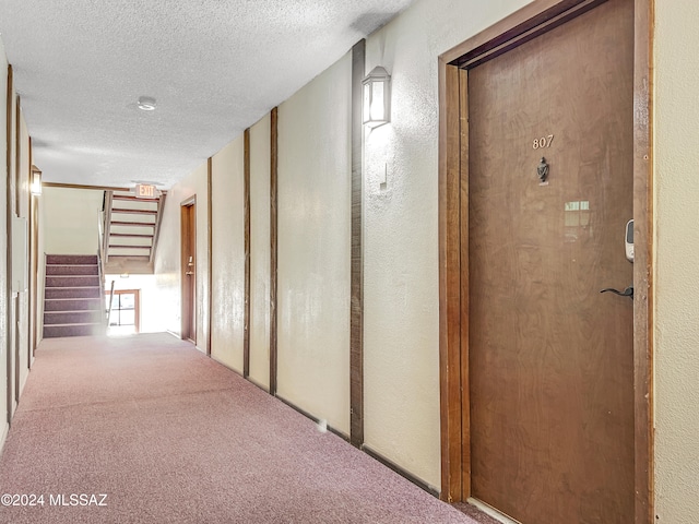 hallway with carpet and a textured ceiling