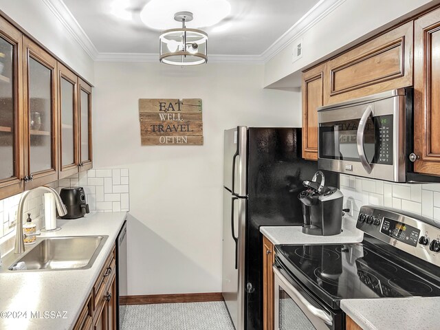 kitchen with appliances with stainless steel finishes, tasteful backsplash, ornamental molding, sink, and light tile patterned floors