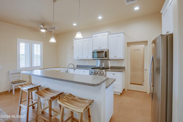 kitchen featuring white cabinetry, an island with sink, stainless steel appliances, and decorative light fixtures