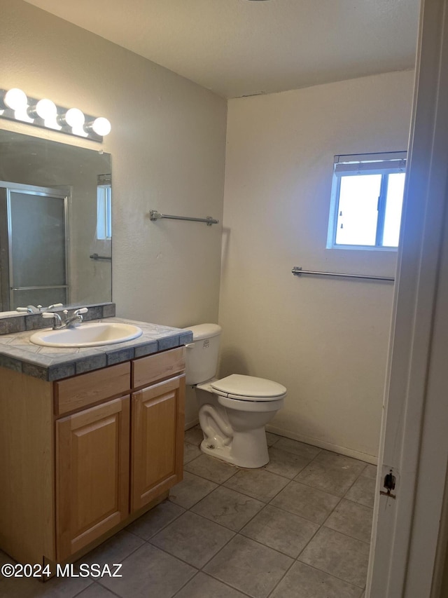 bathroom with toilet, vanity, and tile patterned floors