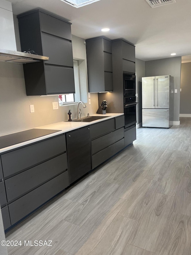 kitchen with gray cabinetry, sink, wall chimney exhaust hood, and black appliances