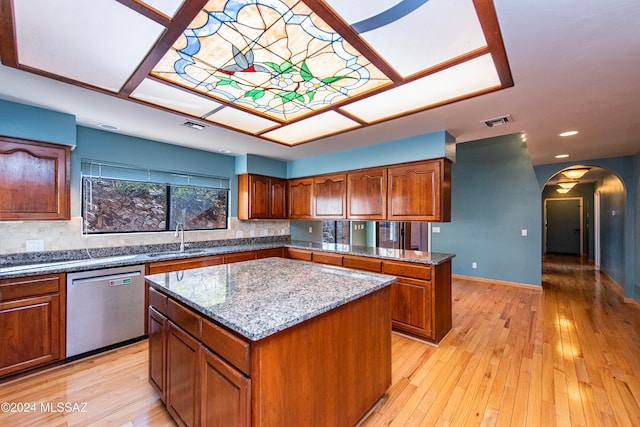 kitchen featuring light stone countertops, sink, light hardwood / wood-style flooring, dishwasher, and a center island