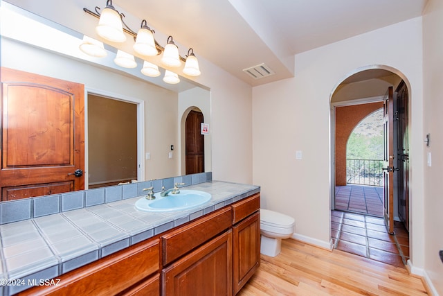 bathroom featuring toilet, vanity, and hardwood / wood-style flooring