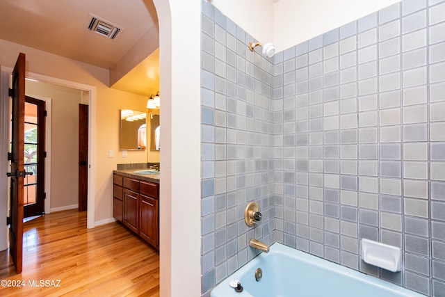 bathroom featuring vanity, hardwood / wood-style flooring, and tiled shower / bath