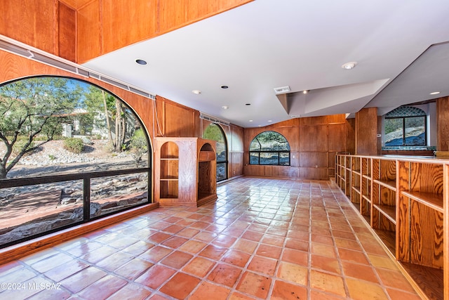 interior space with light tile patterned floors and wooden walls