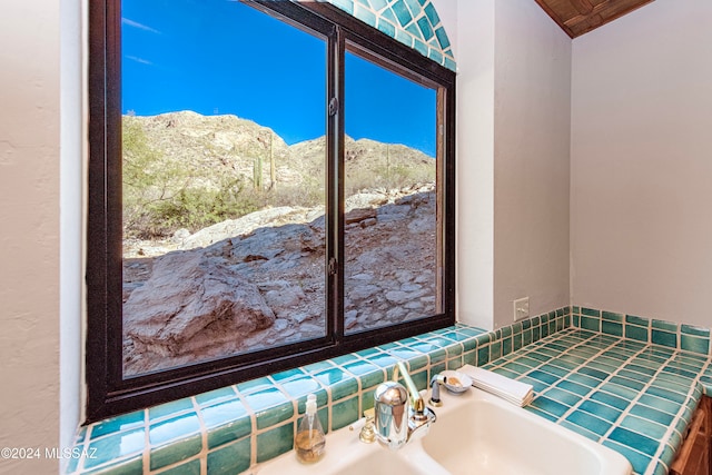 bathroom with a bathing tub, a mountain view, and sink