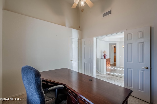 office area featuring baseboards, visible vents, a ceiling fan, a towering ceiling, and light tile patterned flooring