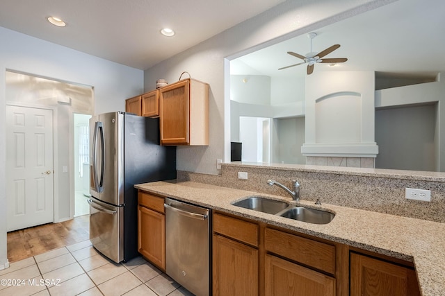 kitchen with light stone counters, stainless steel appliances, ceiling fan, sink, and light tile patterned floors