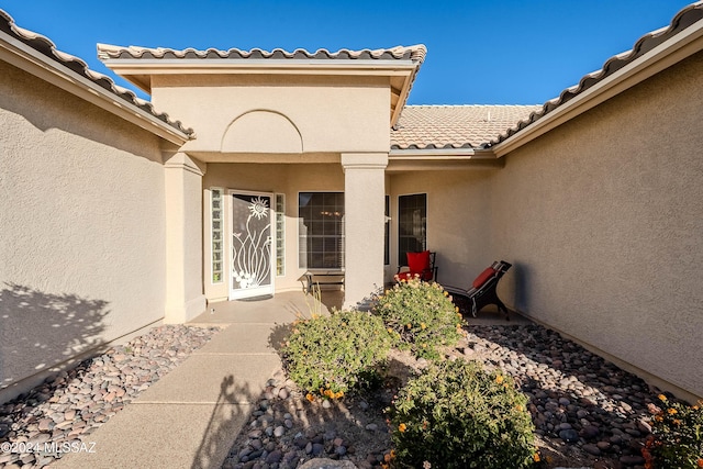 doorway to property with a tile roof and stucco siding