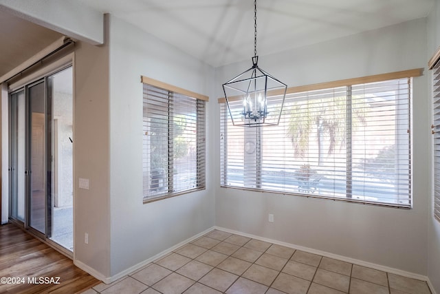 unfurnished dining area with light tile patterned flooring and a notable chandelier