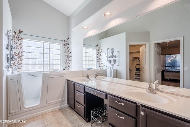 bathroom with tile patterned flooring, vanity, a bath, and lofted ceiling