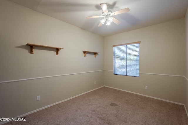 carpeted spare room featuring ceiling fan and baseboards