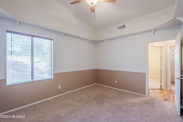 carpeted spare room featuring lofted ceiling, ceiling fan, visible vents, and baseboards