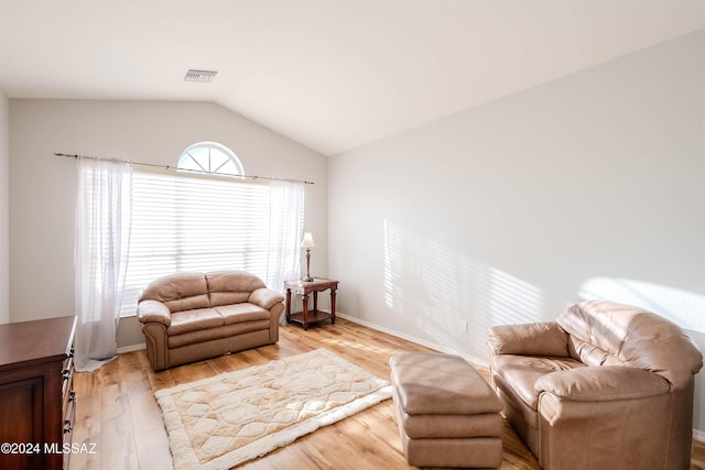 living area with lofted ceiling, light wood-style flooring, visible vents, and a wealth of natural light