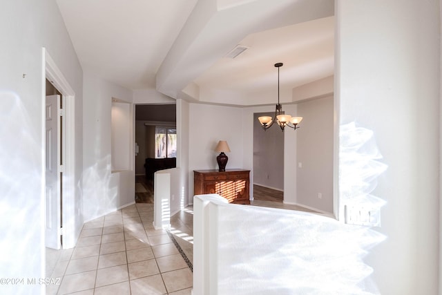 interior space featuring light tile patterned flooring, a raised ceiling, visible vents, and a notable chandelier