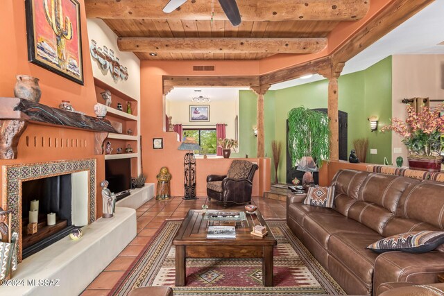 tiled living room with ceiling fan, a fireplace, beam ceiling, built in shelves, and wooden ceiling