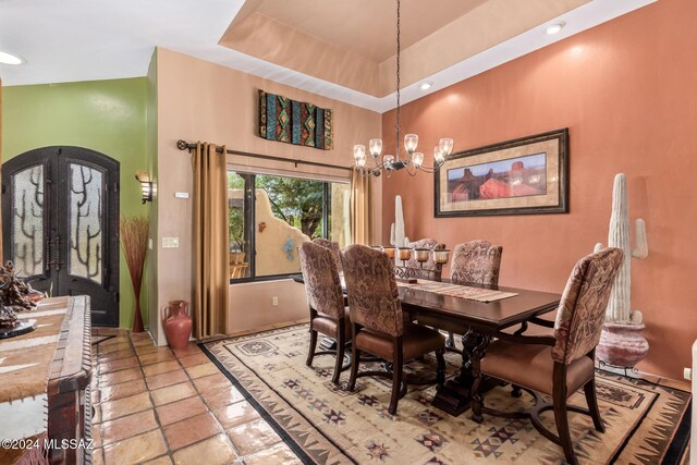 dining space featuring a high ceiling, an inviting chandelier, french doors, and a tray ceiling