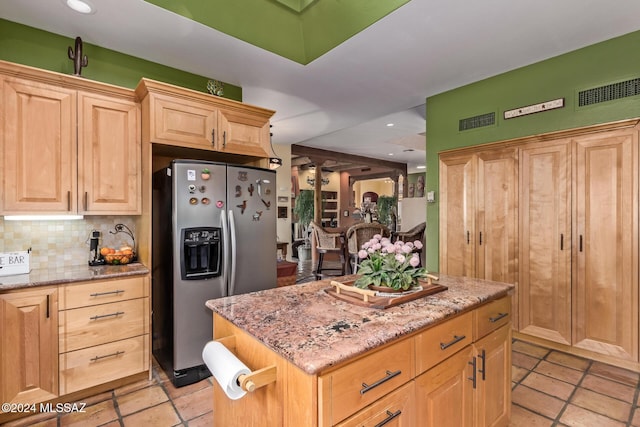 kitchen featuring tasteful backsplash, a center island, light stone countertops, light brown cabinets, and stainless steel fridge