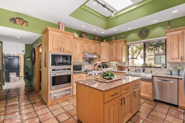 kitchen featuring a skylight, backsplash, black appliances, and a center island