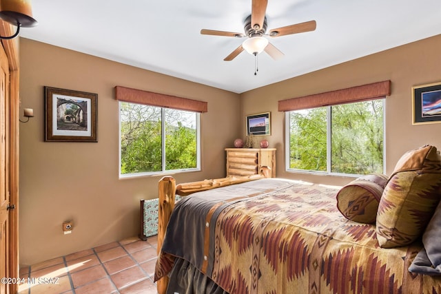 tiled bedroom featuring ceiling fan and multiple windows