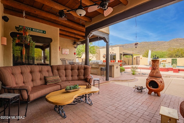 view of patio / terrace with ceiling fan, grilling area, an outdoor kitchen, and a mountain view