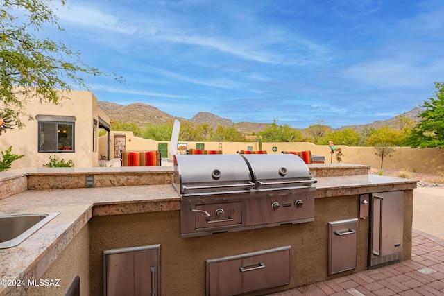 view of patio / terrace featuring exterior kitchen, sink, a mountain view, and area for grilling