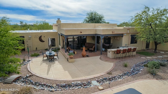 rear view of house featuring a patio and an outdoor bar