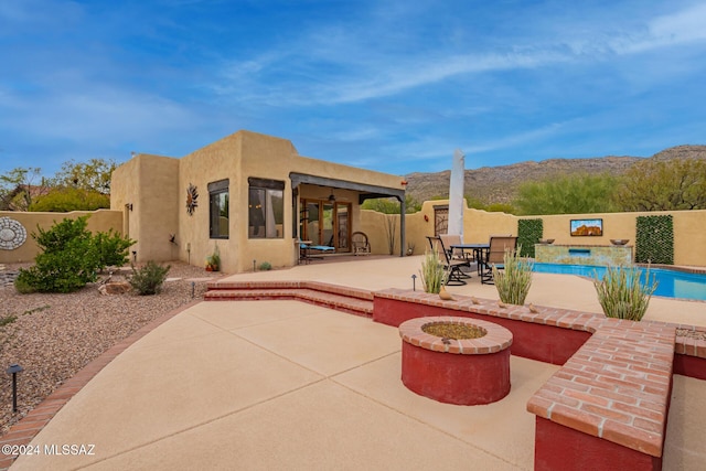 view of patio with a mountain view, a fenced in pool, and a fire pit