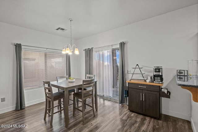 dining area with dark hardwood / wood-style floors and an inviting chandelier