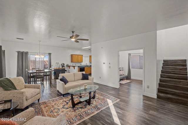 living room with dark hardwood / wood-style floors, sink, and ceiling fan with notable chandelier