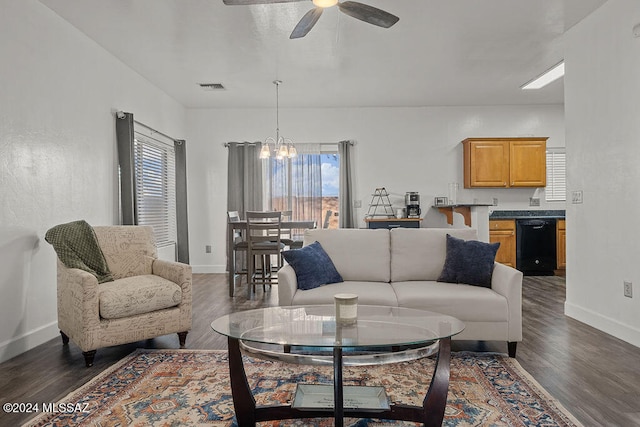 living room featuring dark wood-type flooring, a healthy amount of sunlight, and ceiling fan with notable chandelier