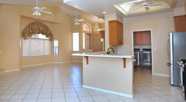 tiled dining room with high vaulted ceiling, washer and dryer, and a notable chandelier