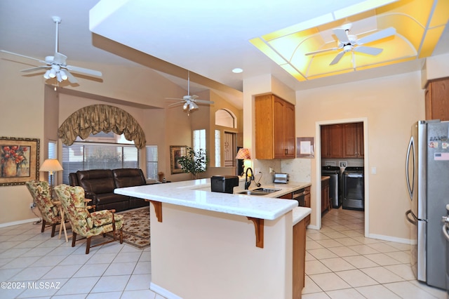 kitchen featuring kitchen peninsula, washing machine and dryer, a breakfast bar area, and sink