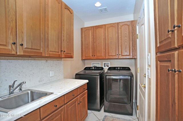 washroom featuring cabinets, light tile patterned floors, washing machine and dryer, and sink