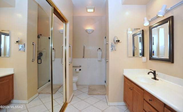 bathroom featuring tile patterned floors, vanity, toilet, and a shower with shower door