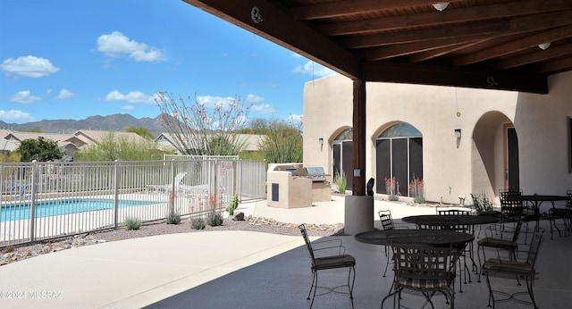 view of patio with a mountain view, exterior kitchen, and a community pool