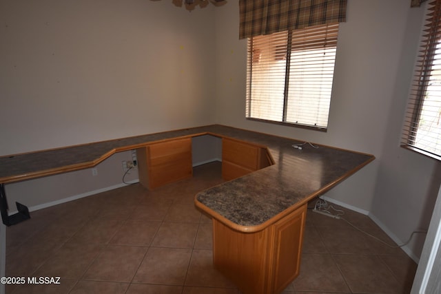 unfurnished office featuring built in study area, tile patterned flooring, and baseboards