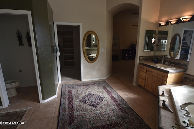 bathroom featuring tile patterned floors, vanity, a bath, and toilet