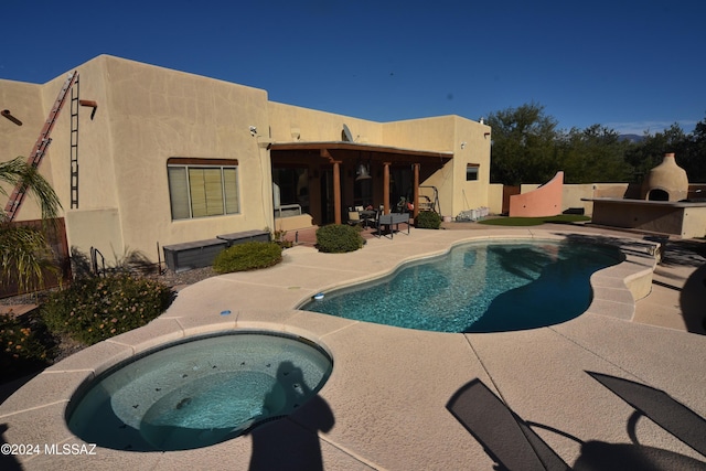 view of swimming pool featuring a patio, an in ground hot tub, and a fireplace